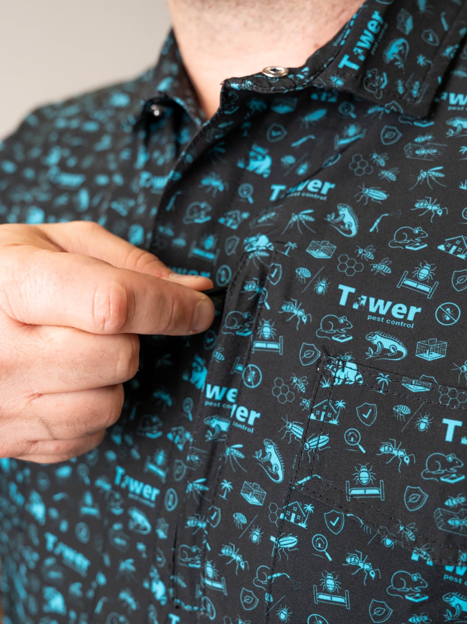 Black polo with a cyan icon pattern and a hand pinching the placket