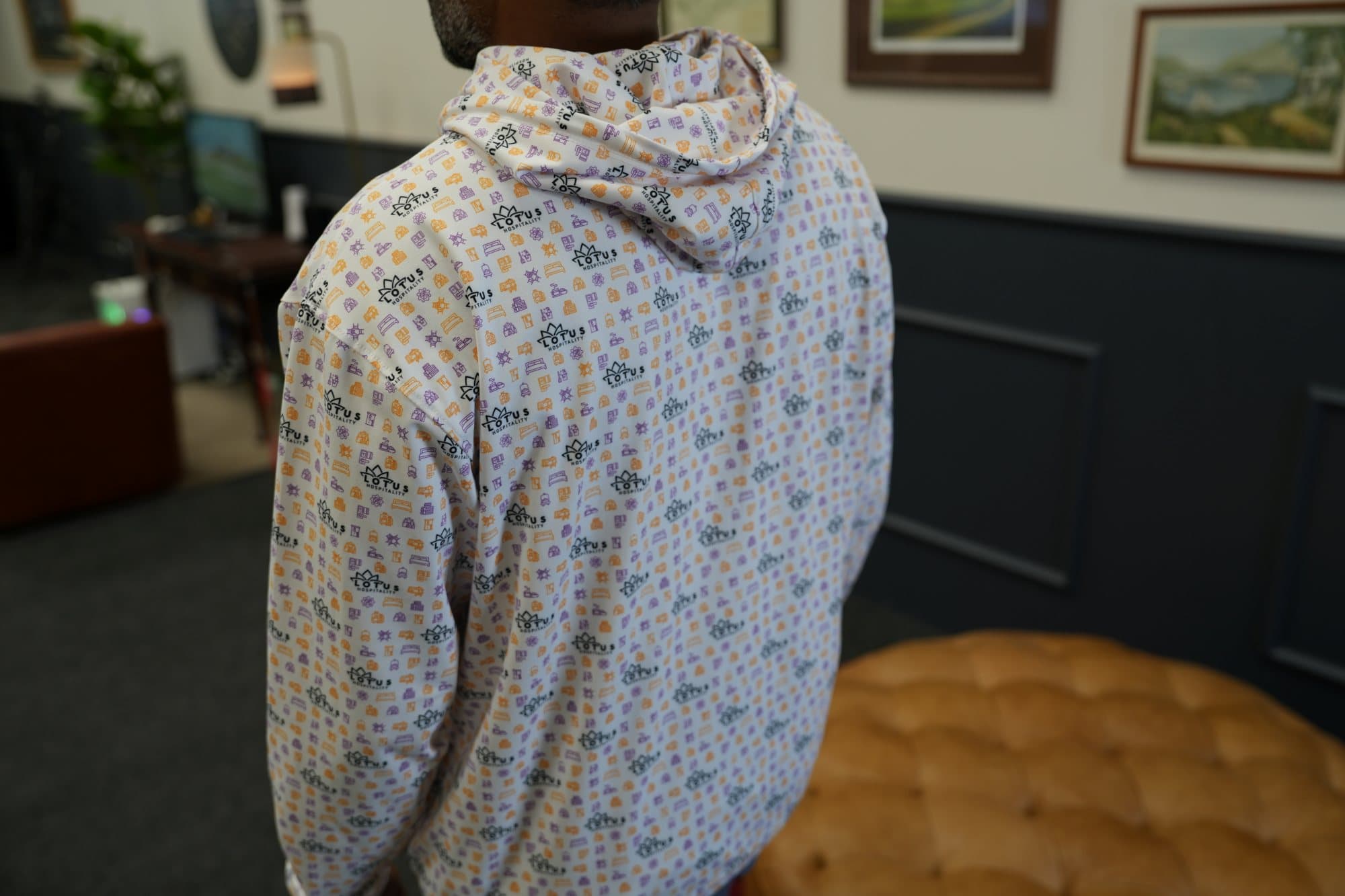 Man seen from behind in a lounge wearing a light all-over print hoodie