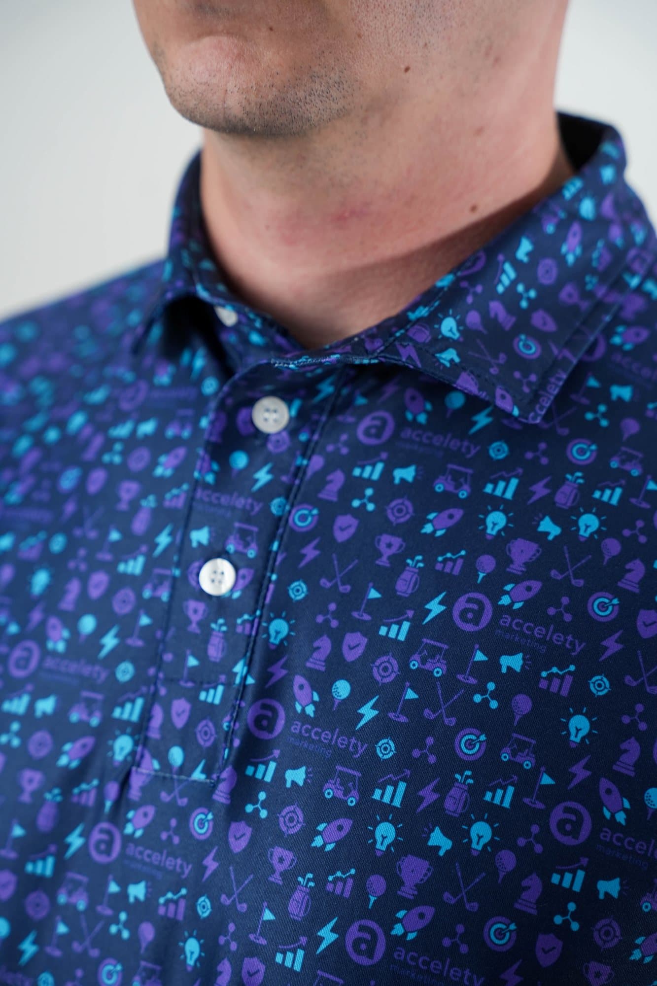 Close-up of the collar of a navy polo with a blue and violet tech icon pattern