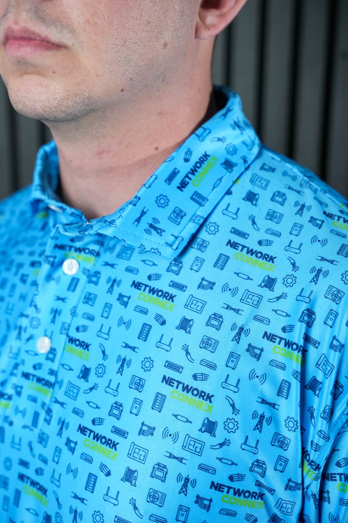 Close-up of the collar of a bright cyan polo with navy network and tower icons