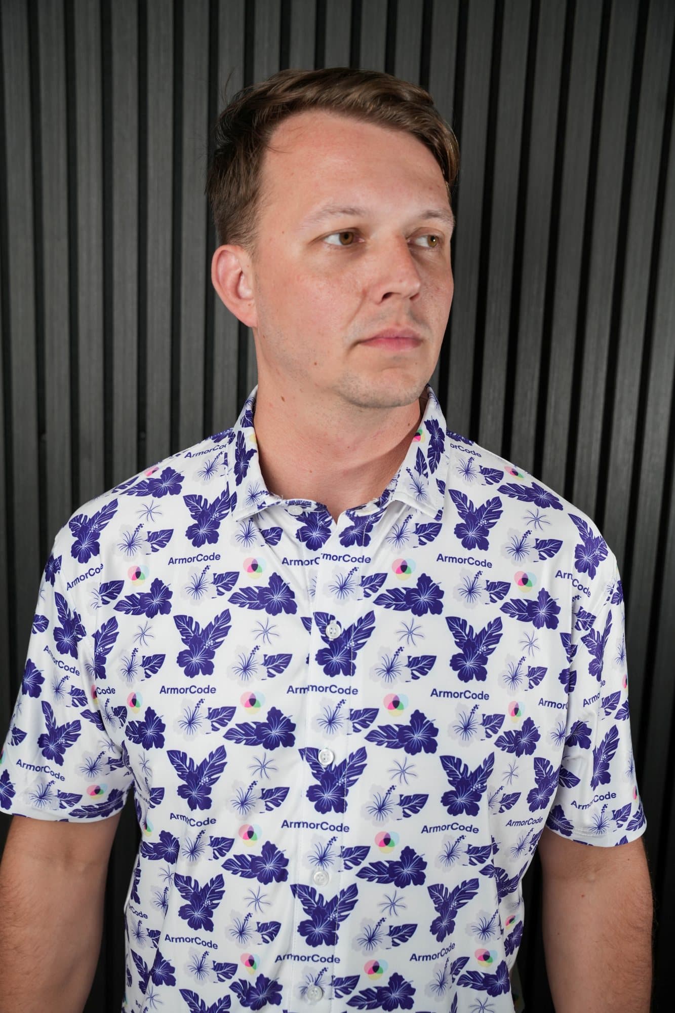 Man in a white polo with a purple and navy bird pattern in a studio