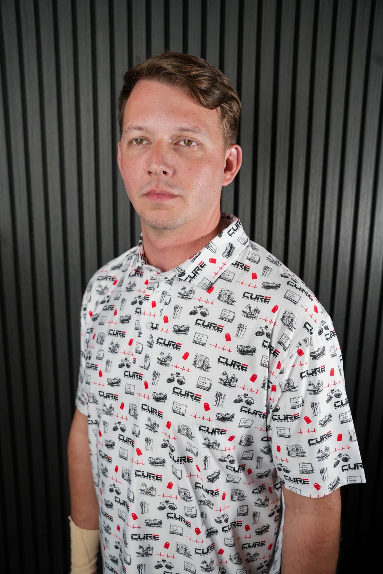 Man in a white polo with red and black icons in a studio