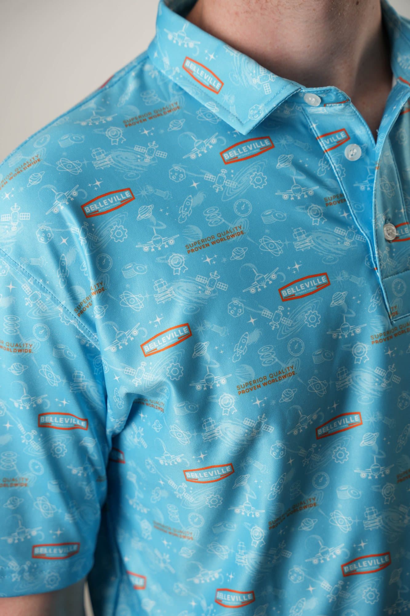 Shoulder and collar close-up of a sky-blue polo with a tonal line-art pattern