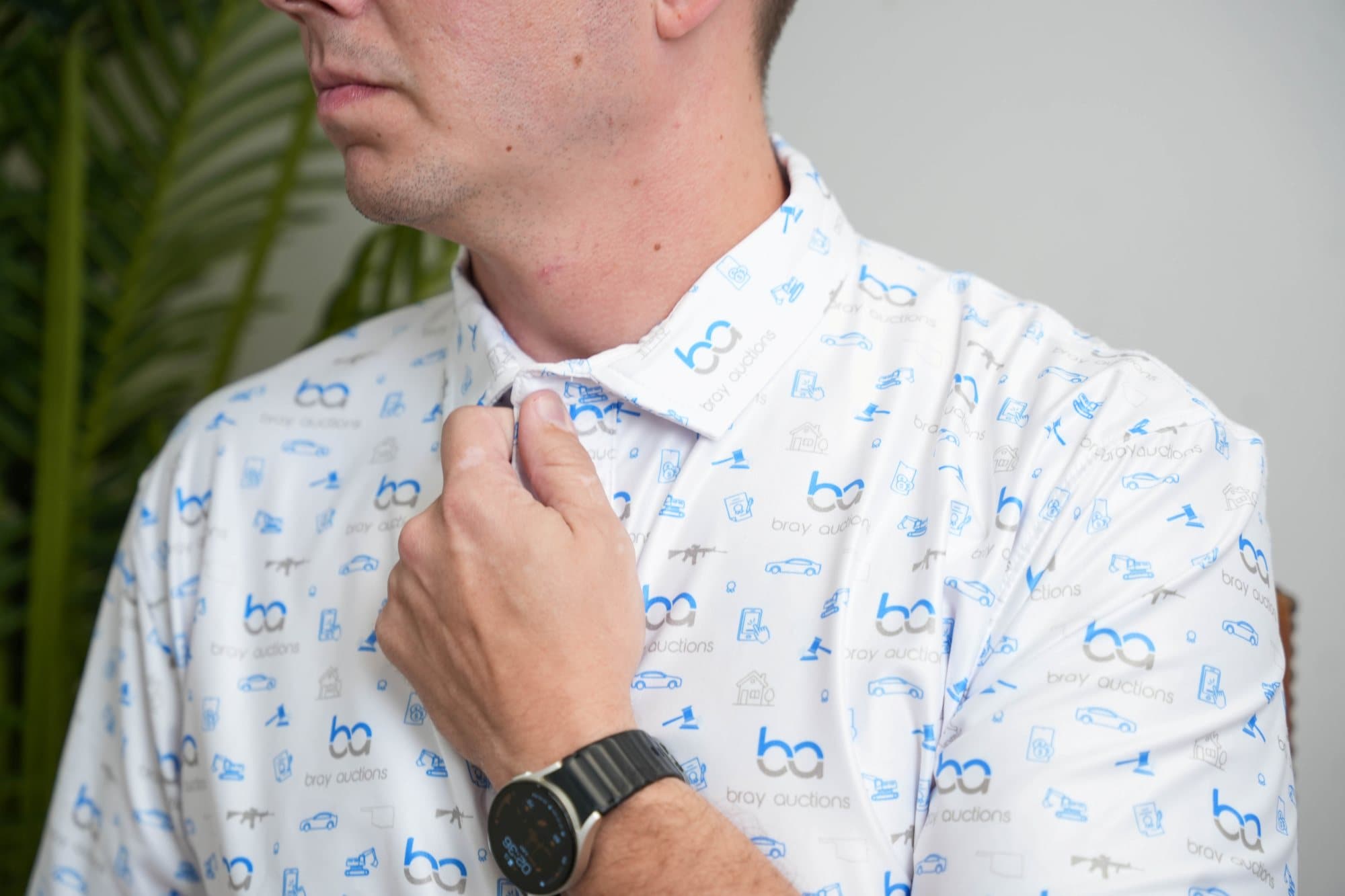 Man adjusting the collar of a white polo with a light-blue icon pattern