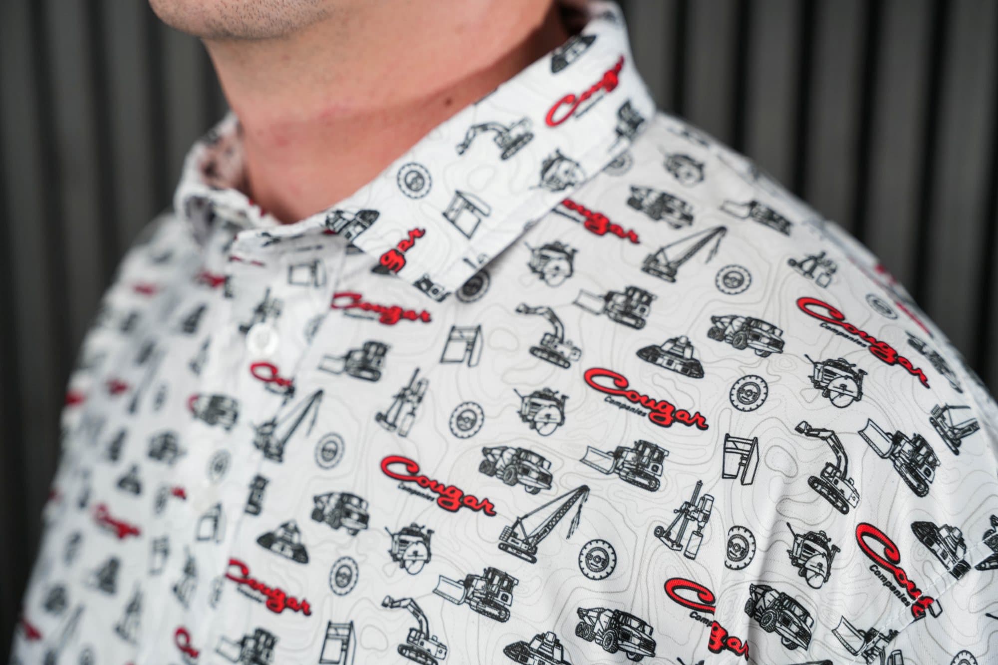 Close-up of a white polo printed with black and red excavators and heavy equipment