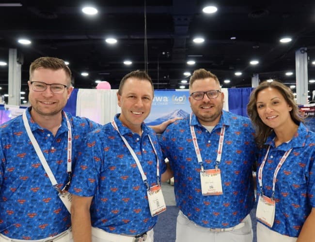 Team of customers in matching custom all-over print Uncorp Wear polos at a trade show