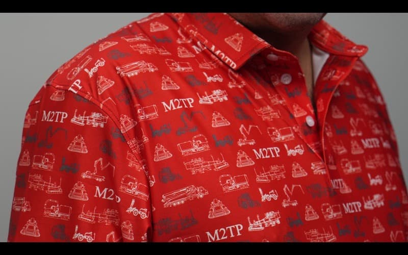 Close-up of a red polo covered in an all-over pattern of white and grey heavy-equipment drawings.