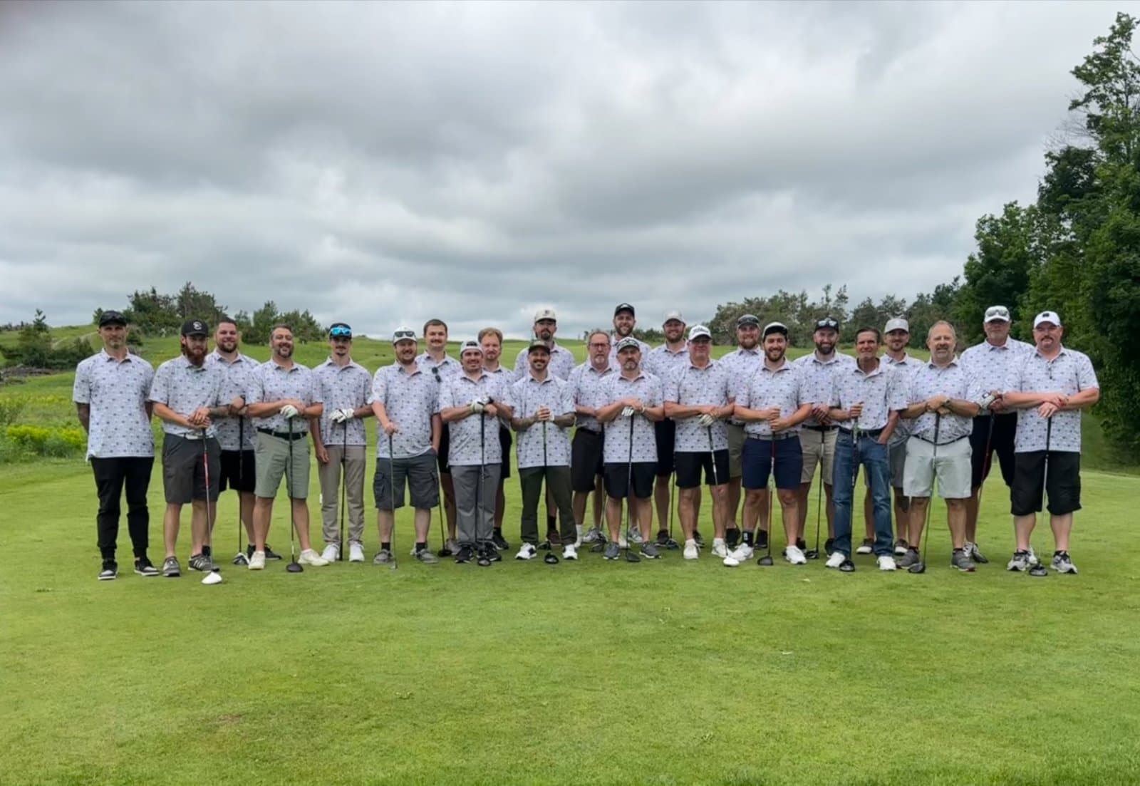 A large group of golfers standing together in matching custom polos on a golf course