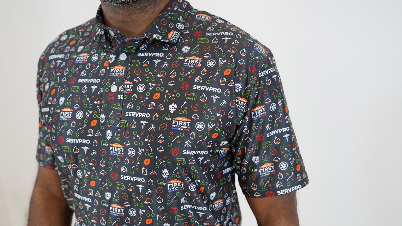 A man in a dark all-over-print work polo covered in a repeating icon and wordmark pattern.