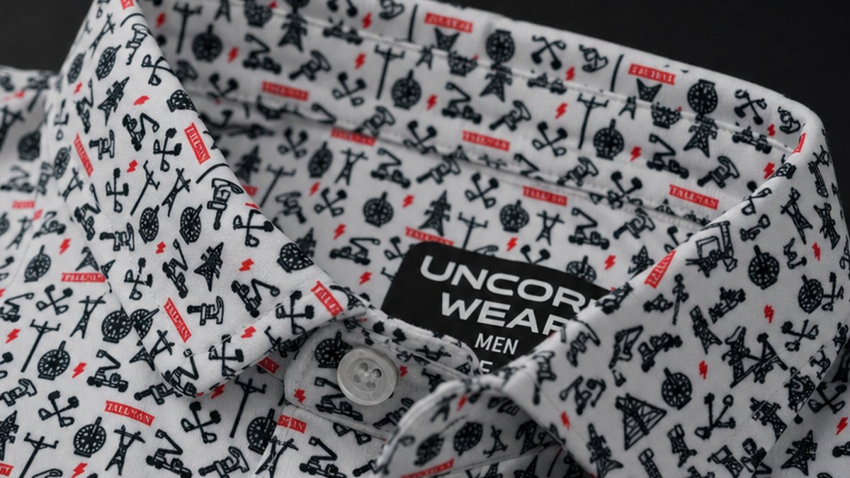 Close-up of a white performance polo collar and placket, printed edge to edge with a small pattern of black utility-line and equipment icons with red accents.