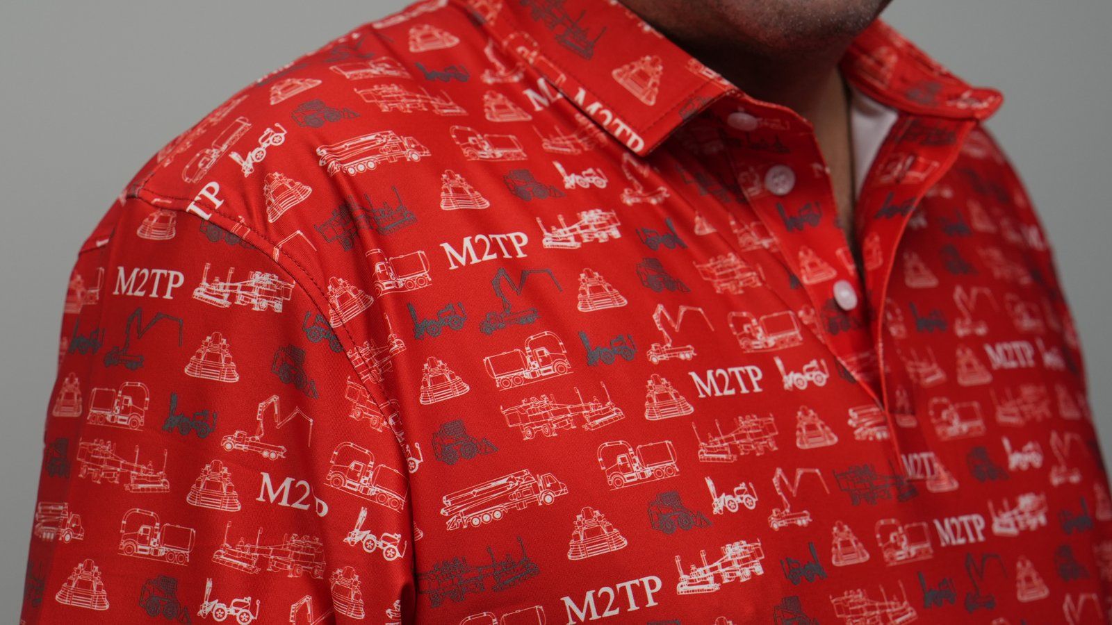 Close-up of a red polo covered in an all-over pattern of white and grey heavy-equipment drawings.